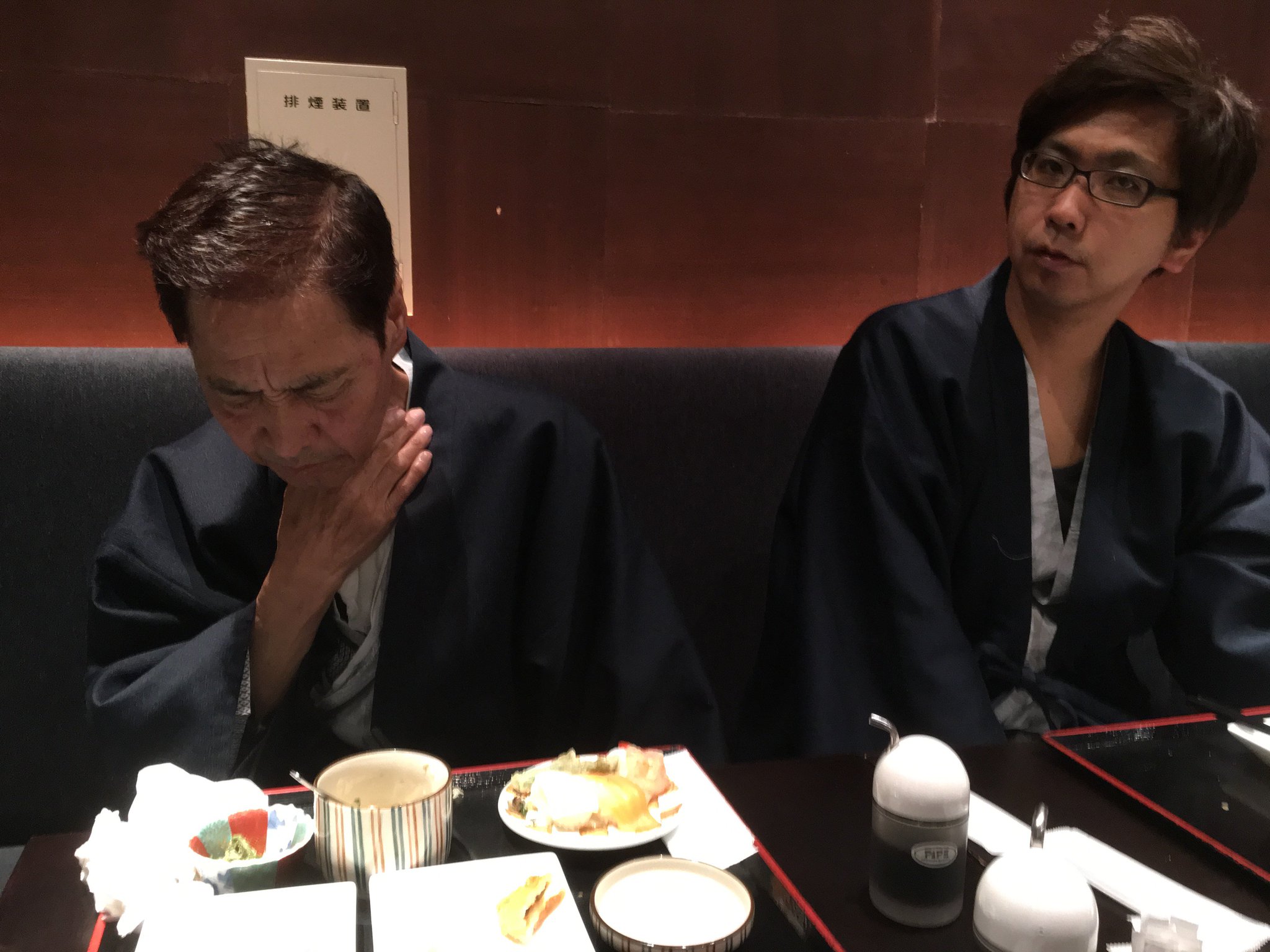 Mr.ハタは飲み込みがうまくできず、咳もひどくなっている。彼の息子Ｔはその隣に座っている。(1年前の英語版ツイートを元に再現しています) https://t.co/4Um9dRRofV
